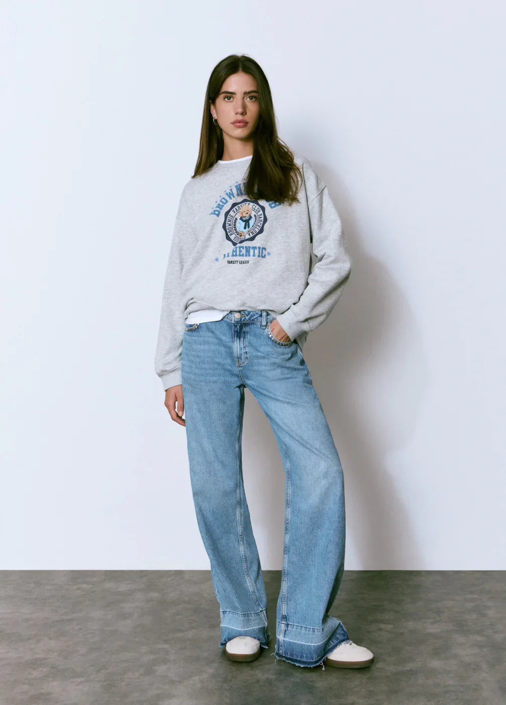 דוגמנית לובשת סווטשירט אפור CHOZEN ומכנסי ג'ינס רחבים, אופנה עדכנית לנשים