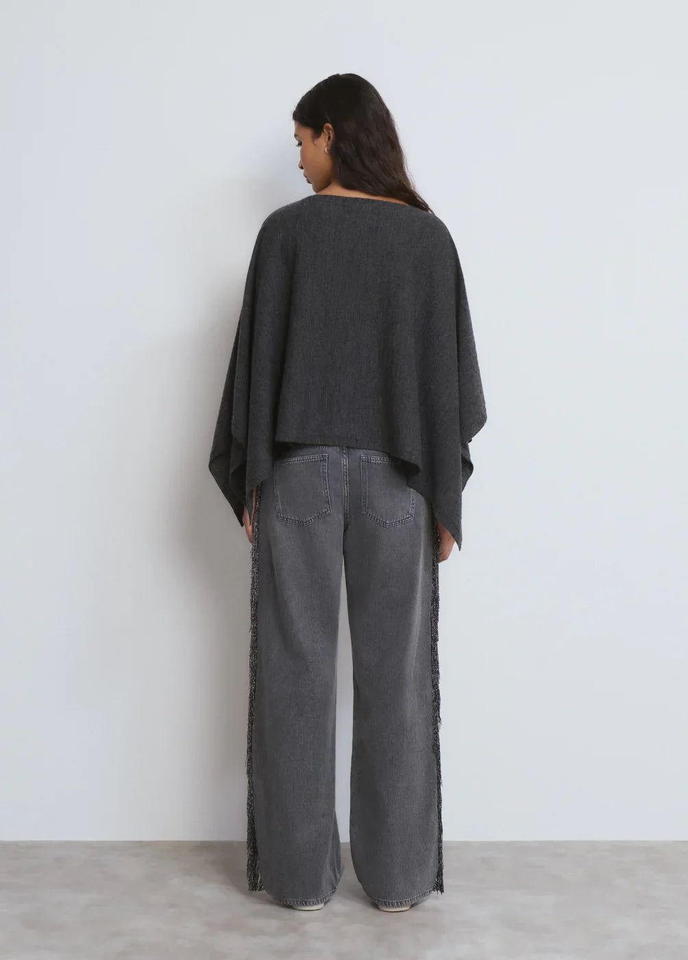 דוגמנית עם עליונית שחורה ומכנסי ג'ינס אפורים רחבים, בסטודיו מינימליסטי, CHOZEN אופנה