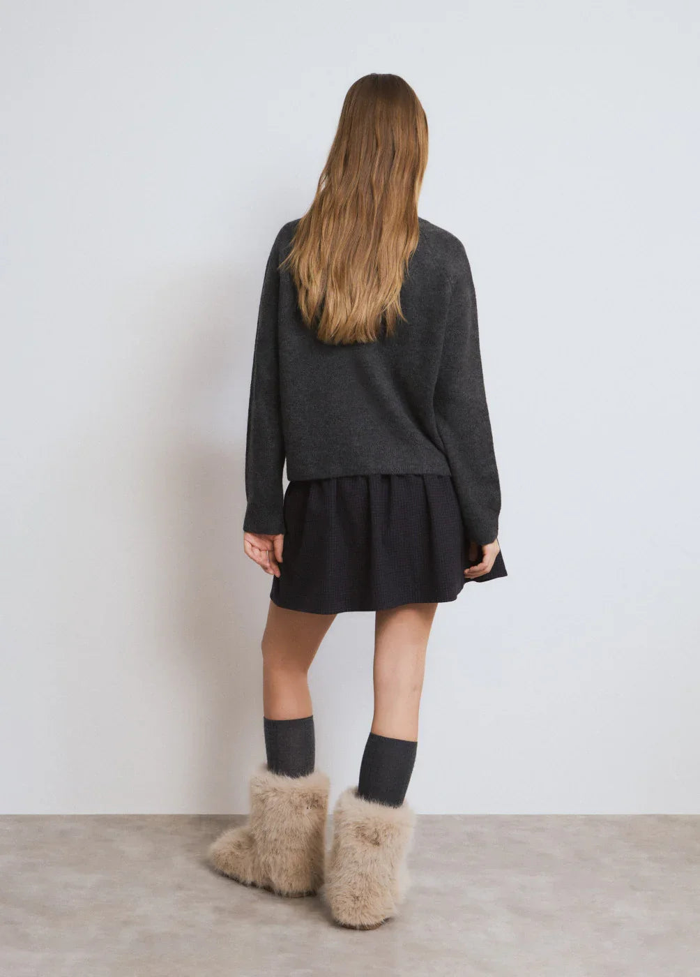 דוגמנית עם סוודר אפור, חצאית שחורה ומגפיים פרוותיים, צילום אופנה CHOZEN