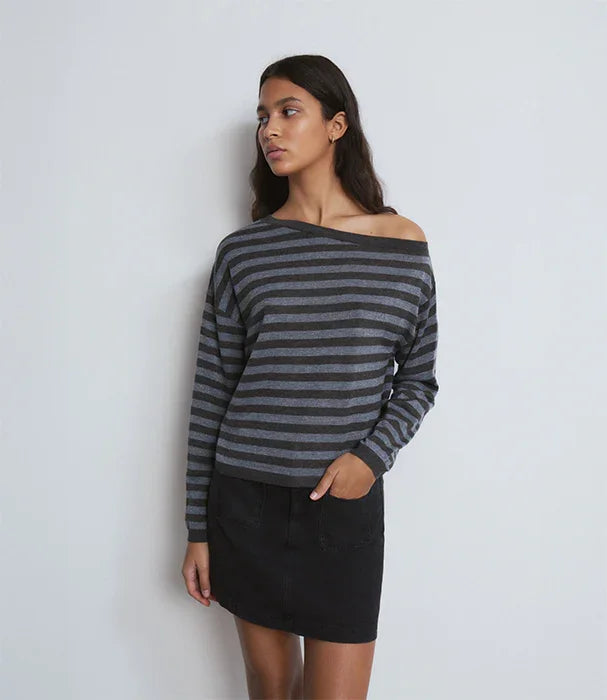 דוגמנית לובשת סוודר פסים אפור ושחור וחצאית שחורה, אופנה עדכנית מבית CHOZEN