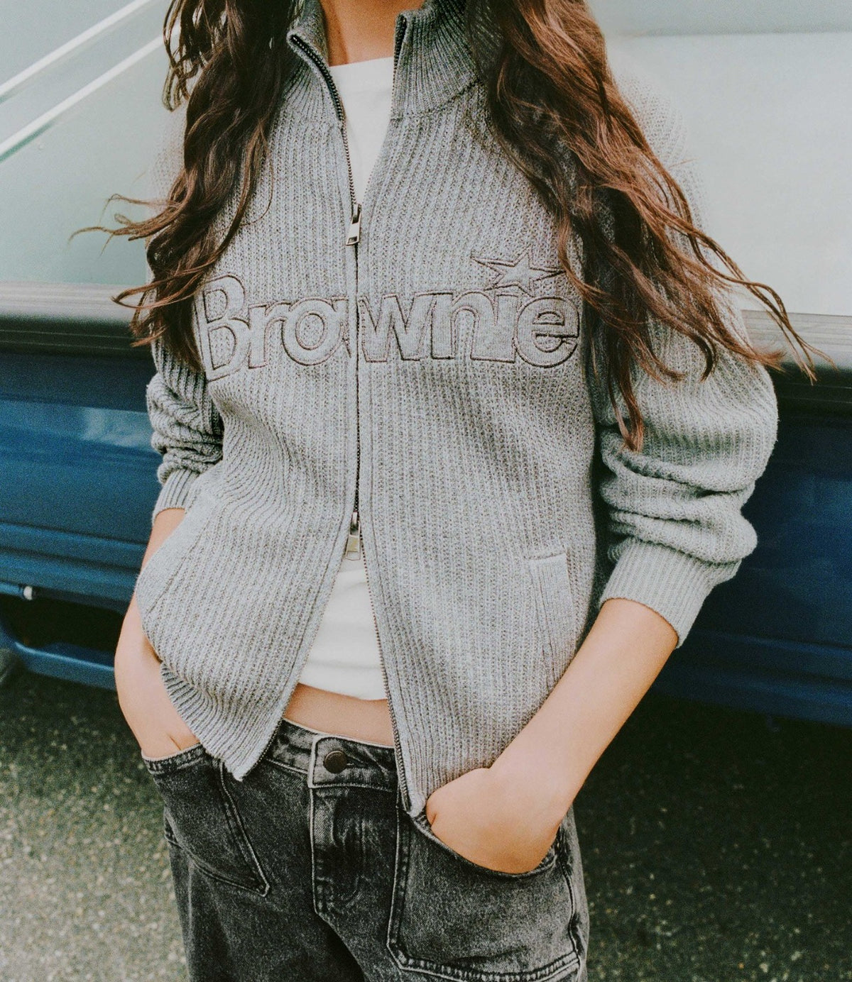 תקריב על קרדיגן אפור עם לוגו Brownie מעל מכנסי הג'ינס - CHOZEN