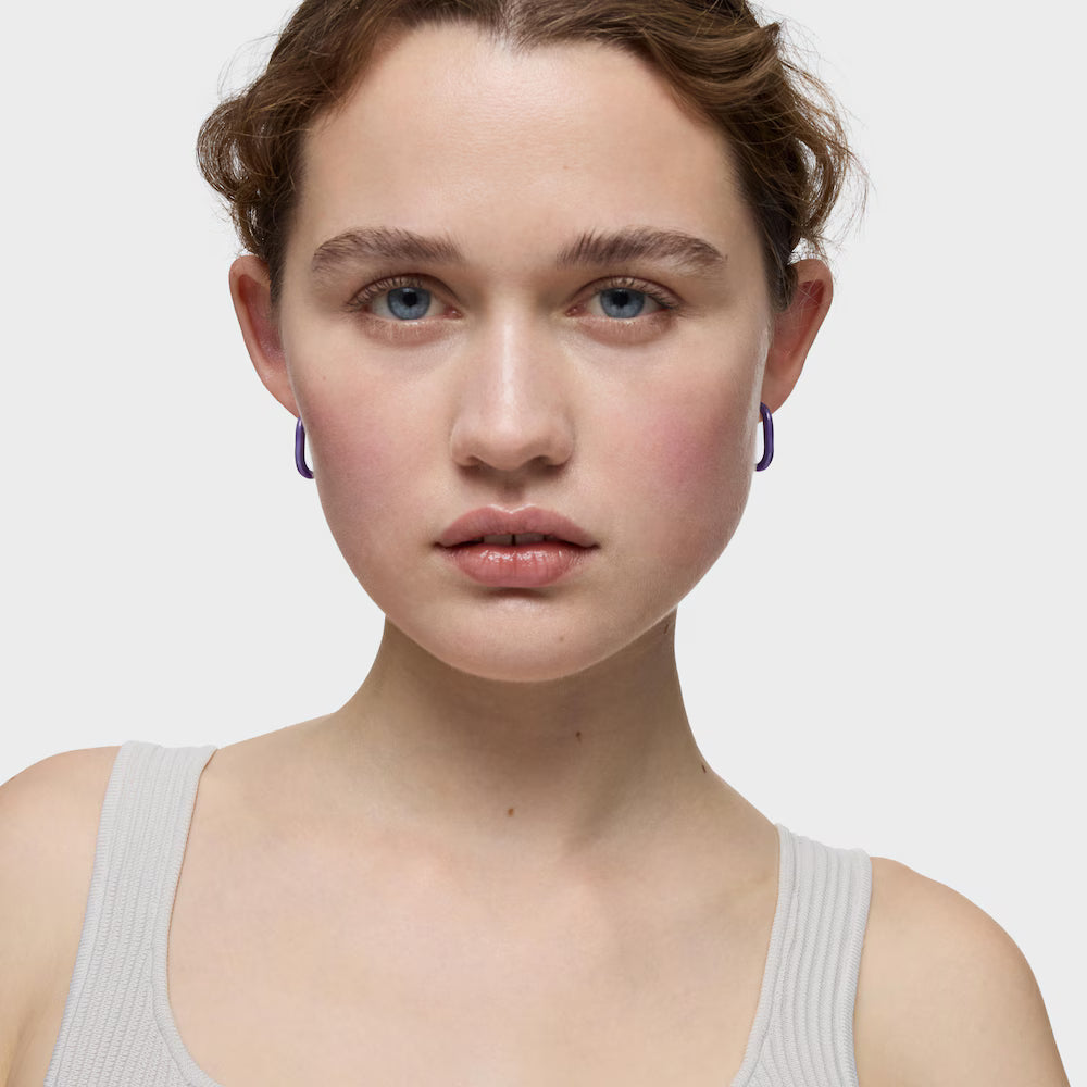 דוגמנית עונדת עגילי חישוק סגולים של מותג יוקרה ברקע לבן, CHOZEN אלפא