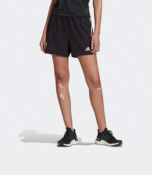 דגם לובשת מכנסי ספורט שחורים של אדידס, נעלי ספורט שחורות, צילום על רקע אפור, CHOZEN