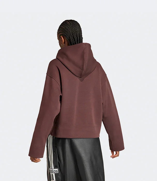 דגם לובש סווטשירט קפוצ'ון חום של אדידס ומכנסי עור שחורים, צילום גב. אופנת CHOZEN