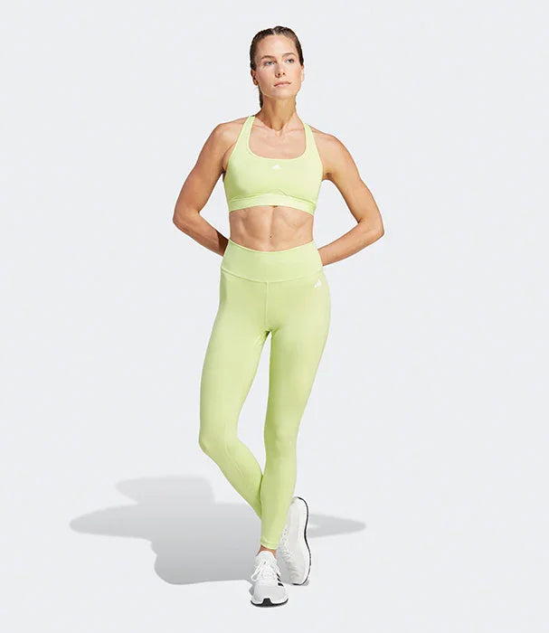 דוגמנית לובשת בגד ספורט צהוב בהיר, טייץ וחזיית ספורט, רקע לבן. CHOZEN בגדי אימון איכותיים.