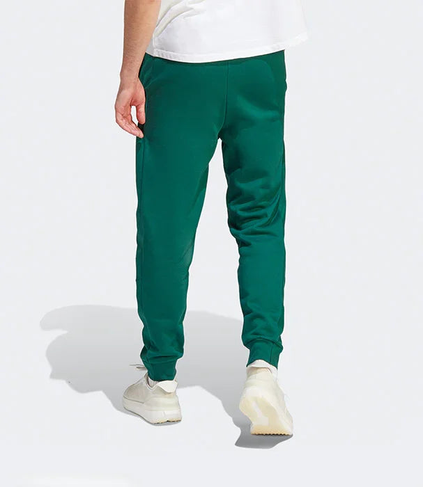 גבר לובש מכנסי טרנינג ירוקים בנעלי ספורט לבנות, צילום מאחור, אופנת גברים CHOZEN