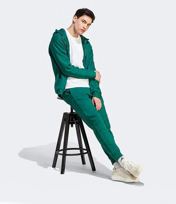 דגם גבר לובש חליפת ספורט ירוקה מבית CHOZEN בישיבה על כיסא, אופנה מודרנית לגברים