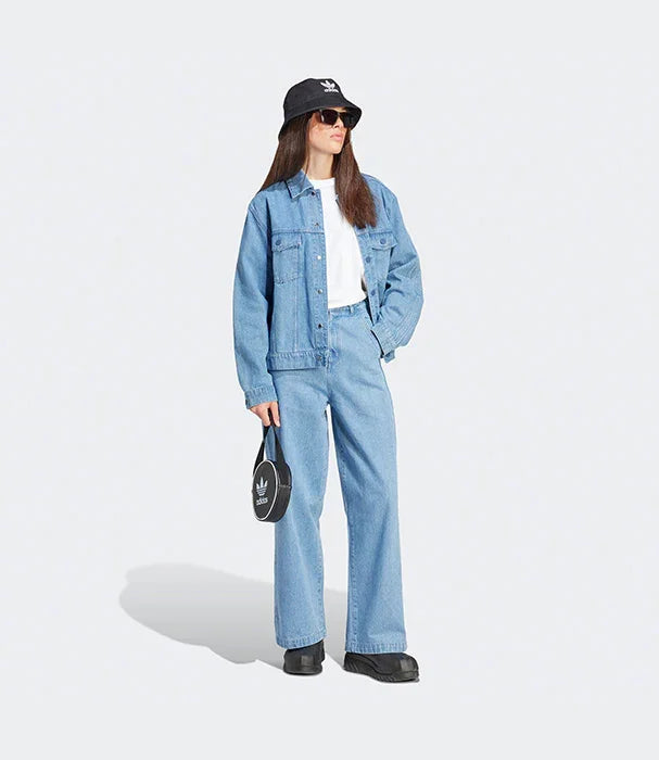 אישה לובשת ג'ינס כחול מלא, חולצה לבנה וכובע באקט, מחזיקה תיק שחור ממותג CHOZEN