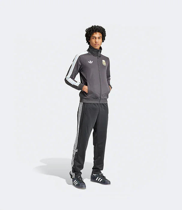 דגם לובש חליפת ספורט אפורה מבית אדידס, עם פסים לבנים וסמל, צילום לקטלוג CHOZEN