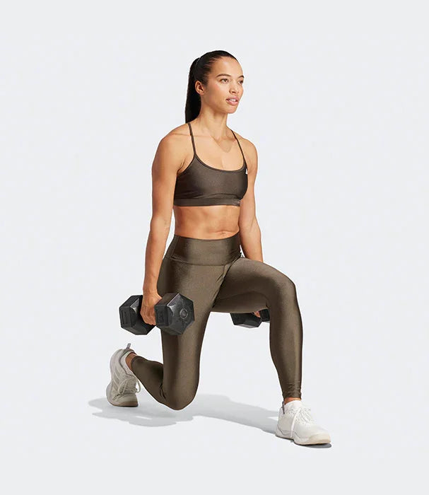 אישה באימון כושר, לובשת בגדי ספורט אפורים, מבית CHOZEN, עושה לאנג' עם משקולות יד