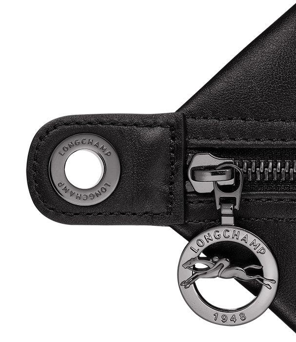 פרט של רוכסן ותליון מתכת ממותג LONGCHAMP על תיק עור שחור יוקרתי, CHOZEN מותגים מובילים