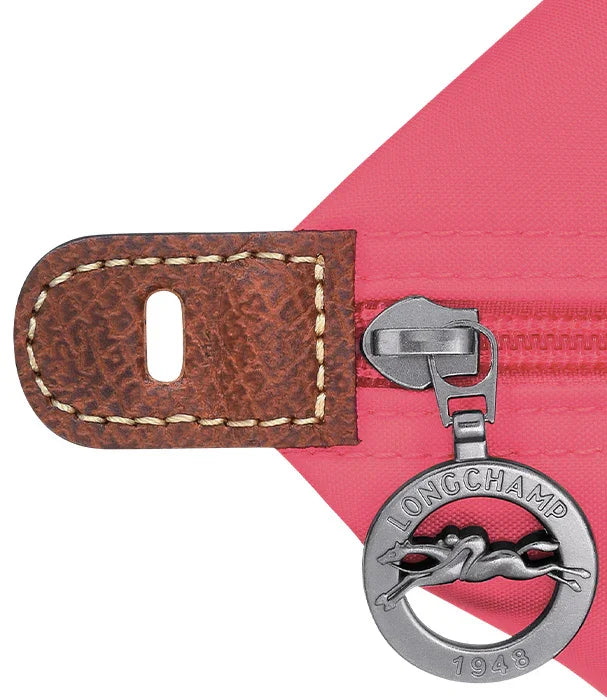 תקריב רוכסן תיק ורוד לונגשאמפ עם תג עור חום וסמל לונגשאמפ, מותגים בינלאומיים CHOZEN