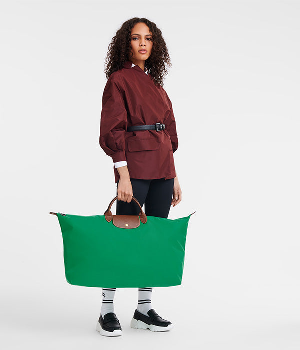 אשה מחזיקה תיק נסיעות ירוק גדול, אופנה מודרנית, בגדי מעצבים מקבוצת אלפא CHOZEN