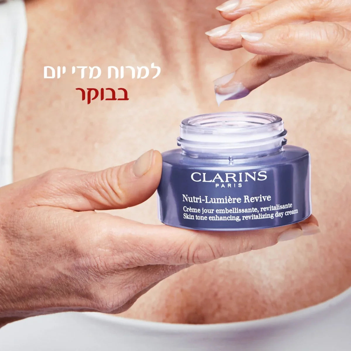 קרם יום קלרינס Nutri-Lumière Revive מוחזק ביד, רקע עור, מוצר טיפוח עור יוקרתי CHOZEN