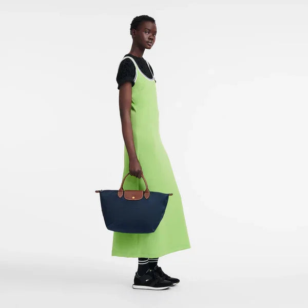 אופנה CHOZEN: דוגמנית בשמלה ירוקה עם תיק כחול ומגפיים, רקע לבן נקי