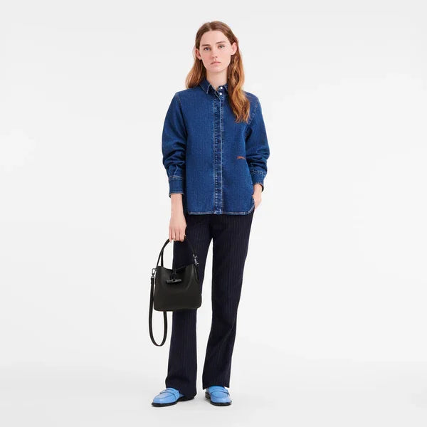 אישה עם חולצת ג'ינס כחולה, מכנס כהה, תיק שחור ונעלי מוקסין כחולות, אופנת CHOZEN