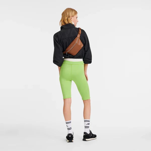 אישה עם תיק צד חום, ג'קט שחור וטייץ ירוק ליים, אופנה ספורטיבית CHOZEN