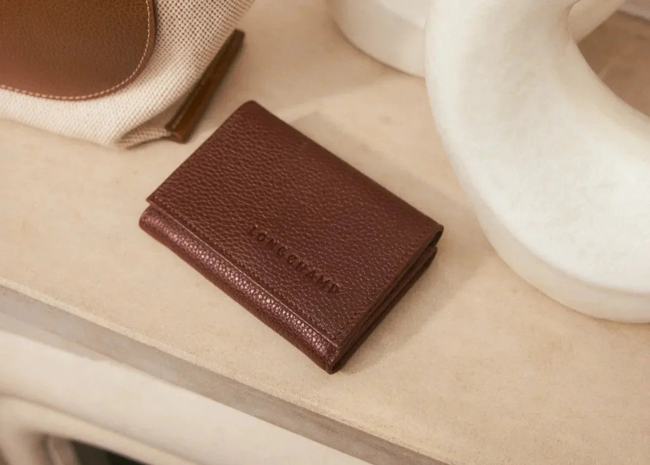 ארנק עור חום יוקרתי ממותג LONGCHAMP על שולחן, מותגי יוקרה ב-CHOZEN