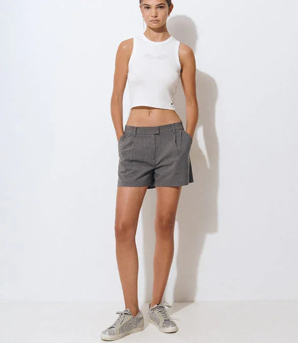 דוגמנית לובשת גופיה לבנה ומכנסיים קצרים אפורים, אופנה טרנדית ב-CHOZEN