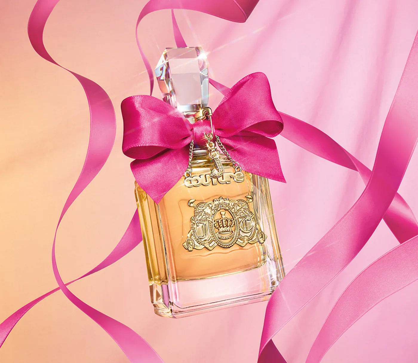 בקבוק בושם יוקרתי עם סרט ורוד על רקע ורוד, מושלם כמתנה לאישה