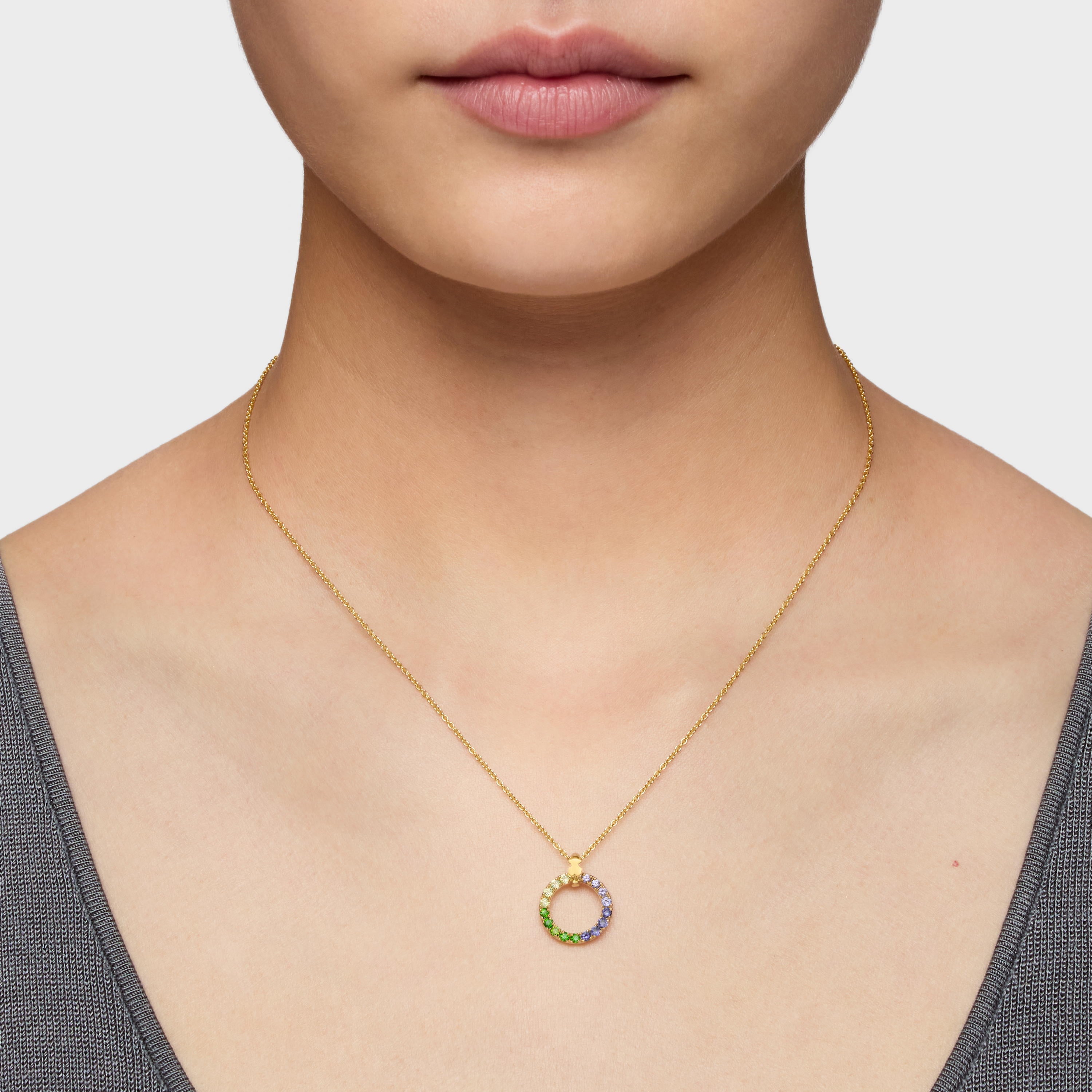 שרשרת זהב עגולה עם תליונים צבעוניים על צוואר של אישה