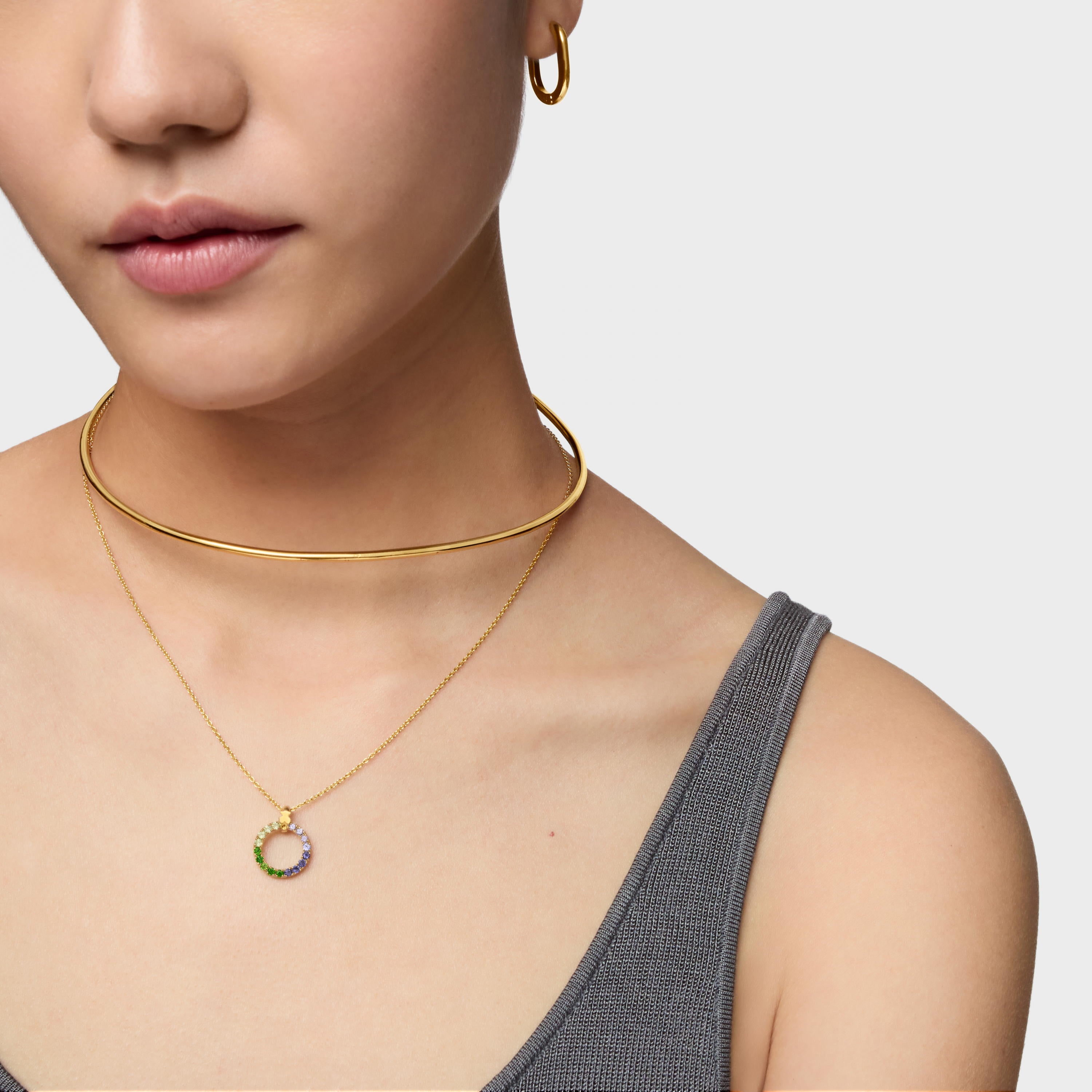 אישה עונדת שרשרת זהב צמודה, שרשרת עדינה עם תליון עגול משובץ אבנים ועגיל חישוק זהב