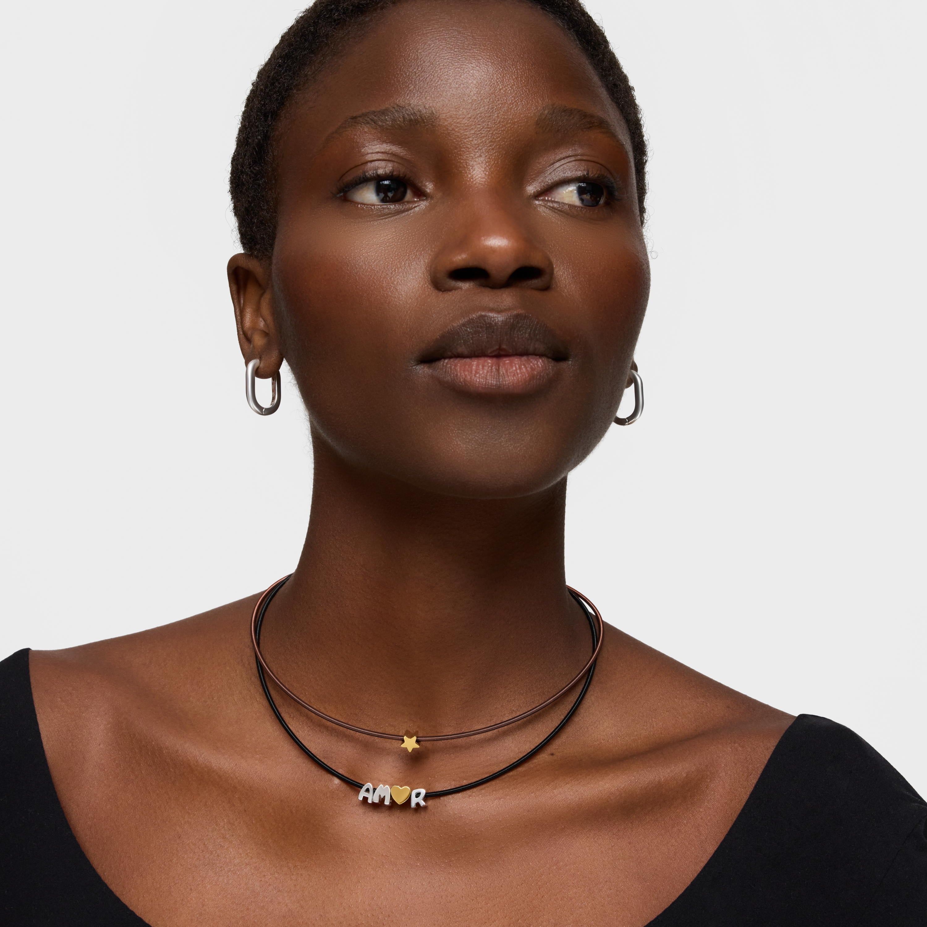 דוגמנית עונדת שרשרת עור עם תליון כוכב קטן ושרשרת עם אותיות AMOR, עגילים כסופים
