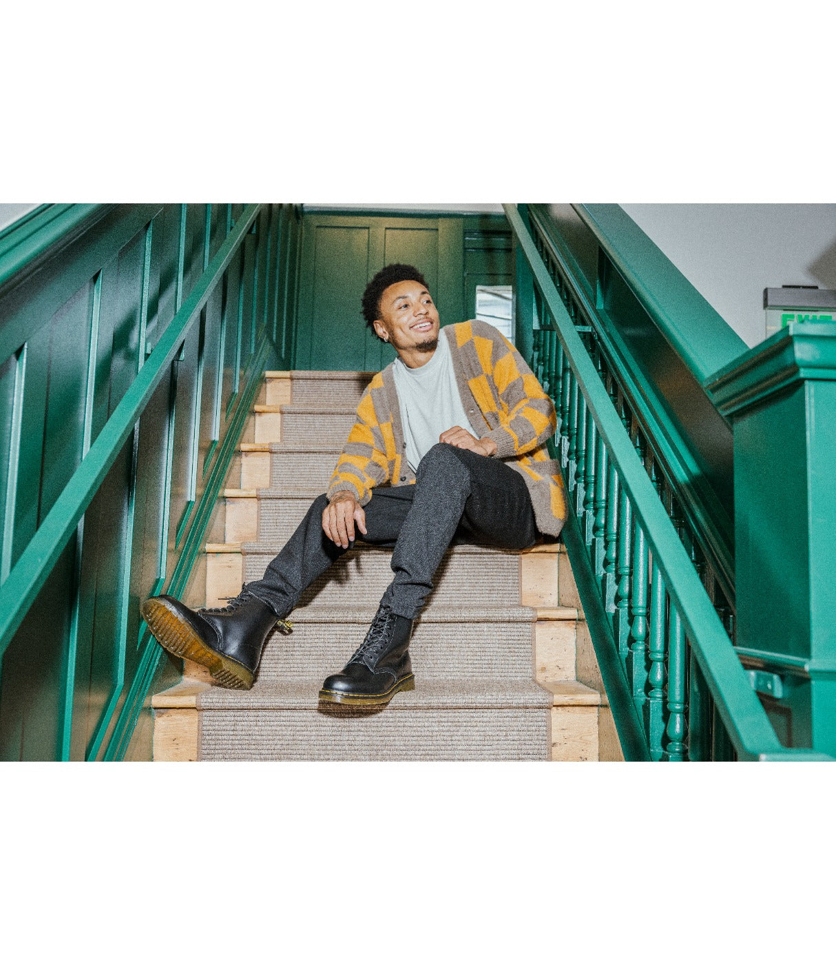 גבר יושב על מדרגות עם מגפי DR. MARTENS 1460 שחורים, מבט לייף-סטייל, מבית CHOZEN
