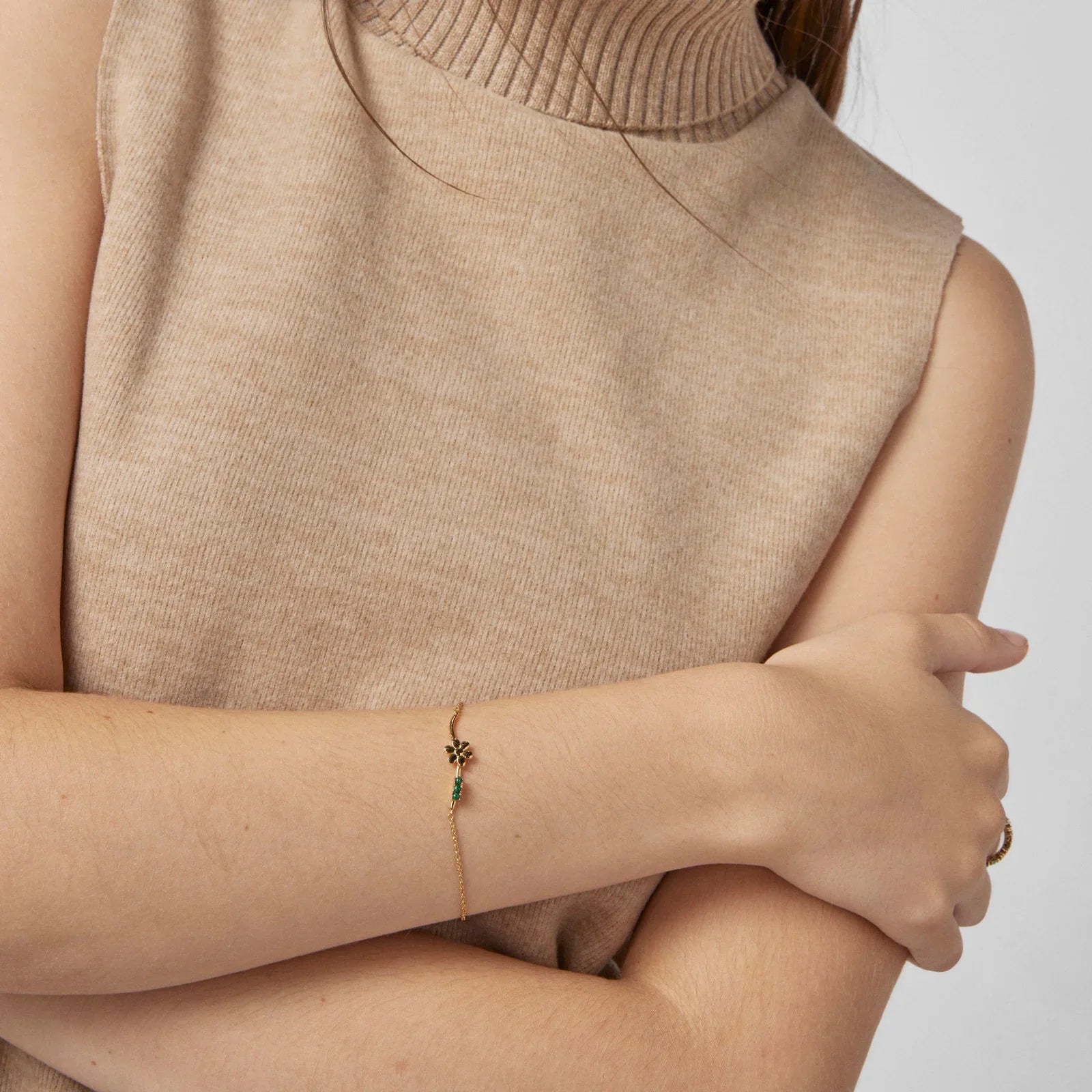 צמיד זהב עדין עם תליון פרח, דוגמנית בלבוש ניטרלי, תכשיטים CHOZEN מבית קבוצת אלפא