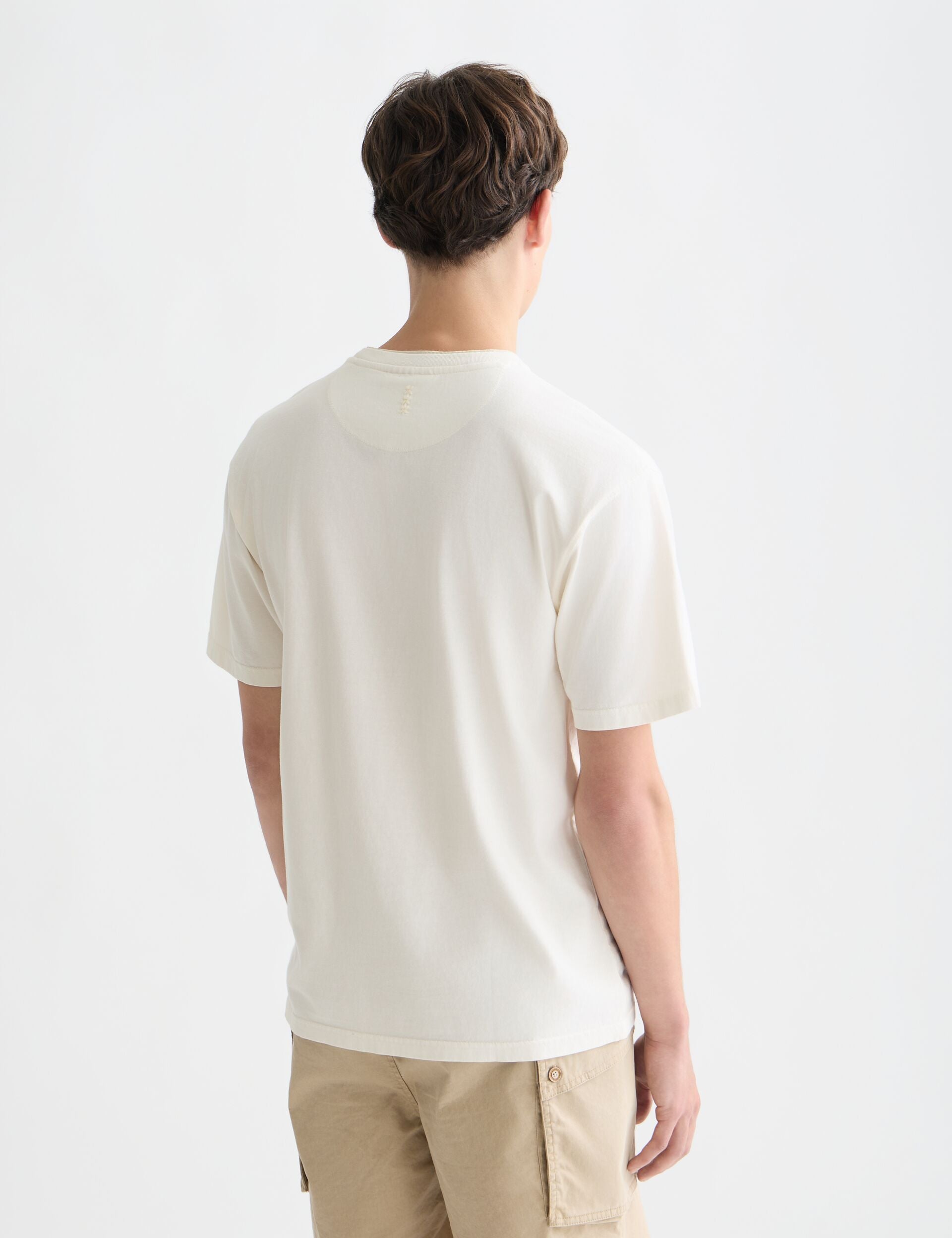 דוגמן עם חולצת טי לבנה ומכנסי בז', צילום בגב בסגנון CHOZEN