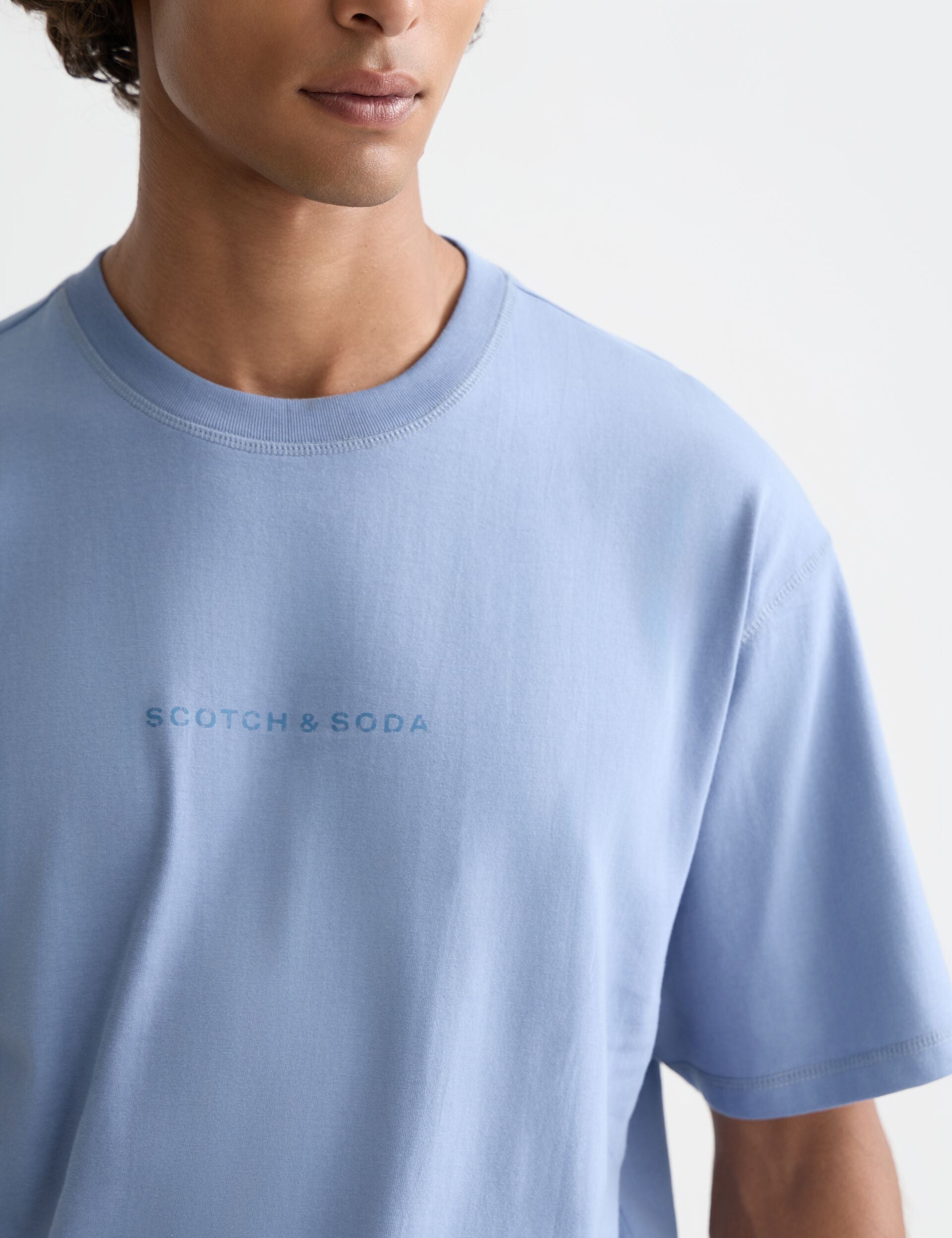 גבר לובש טי שירט תכלת של Scotch & Soda, אופנת גברים יוקרתית ב-CHOZEN