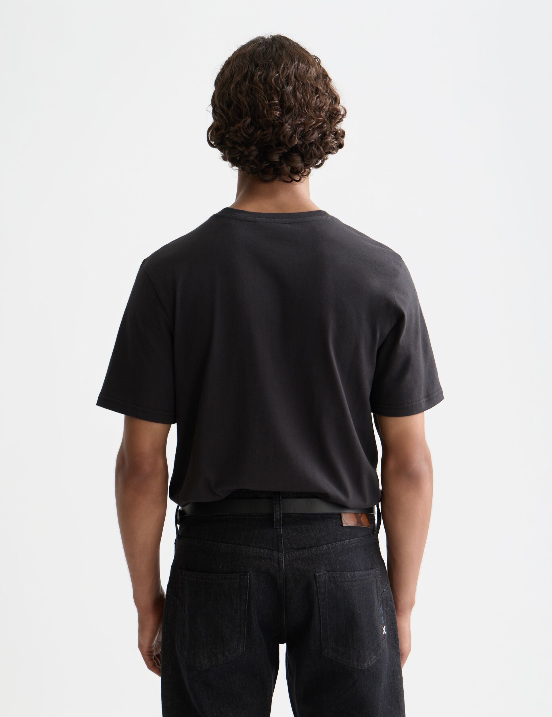 גבר לובש חולצת טי שחורה וג'ינס כהה, צילום גב, אופנת CHOZEN