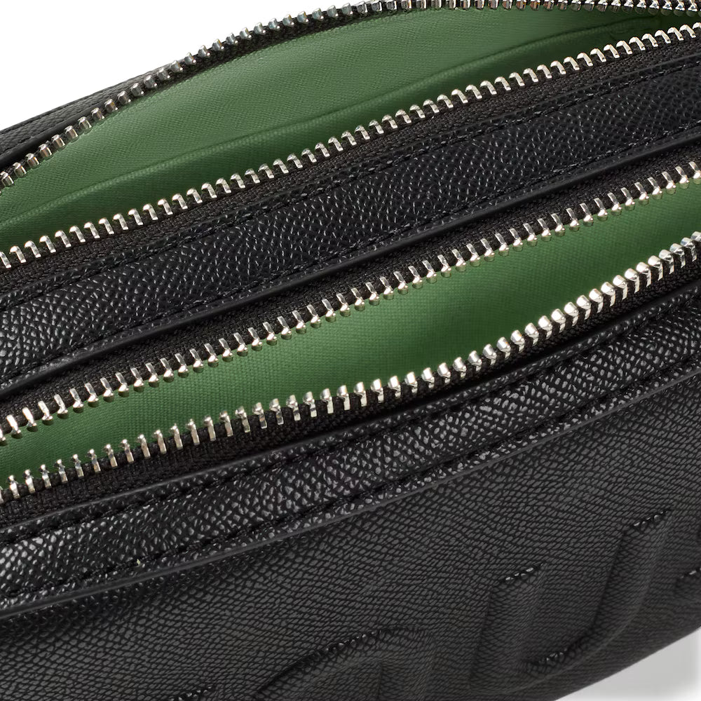 תקריב של תיק עור שחור עם רוכסנים וחלק פנימי ירוק