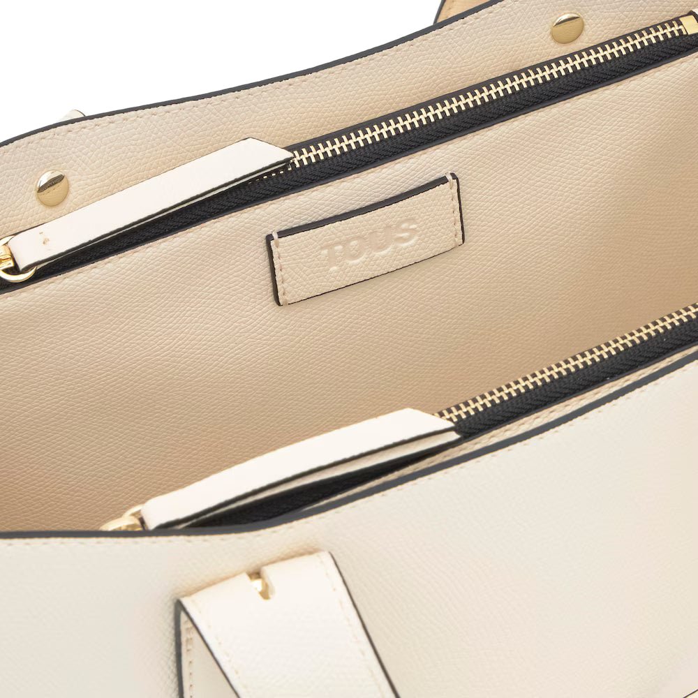 תקריב תיק יד בצבע קרם עם רוכסן זהב ותווית פנימית מעור