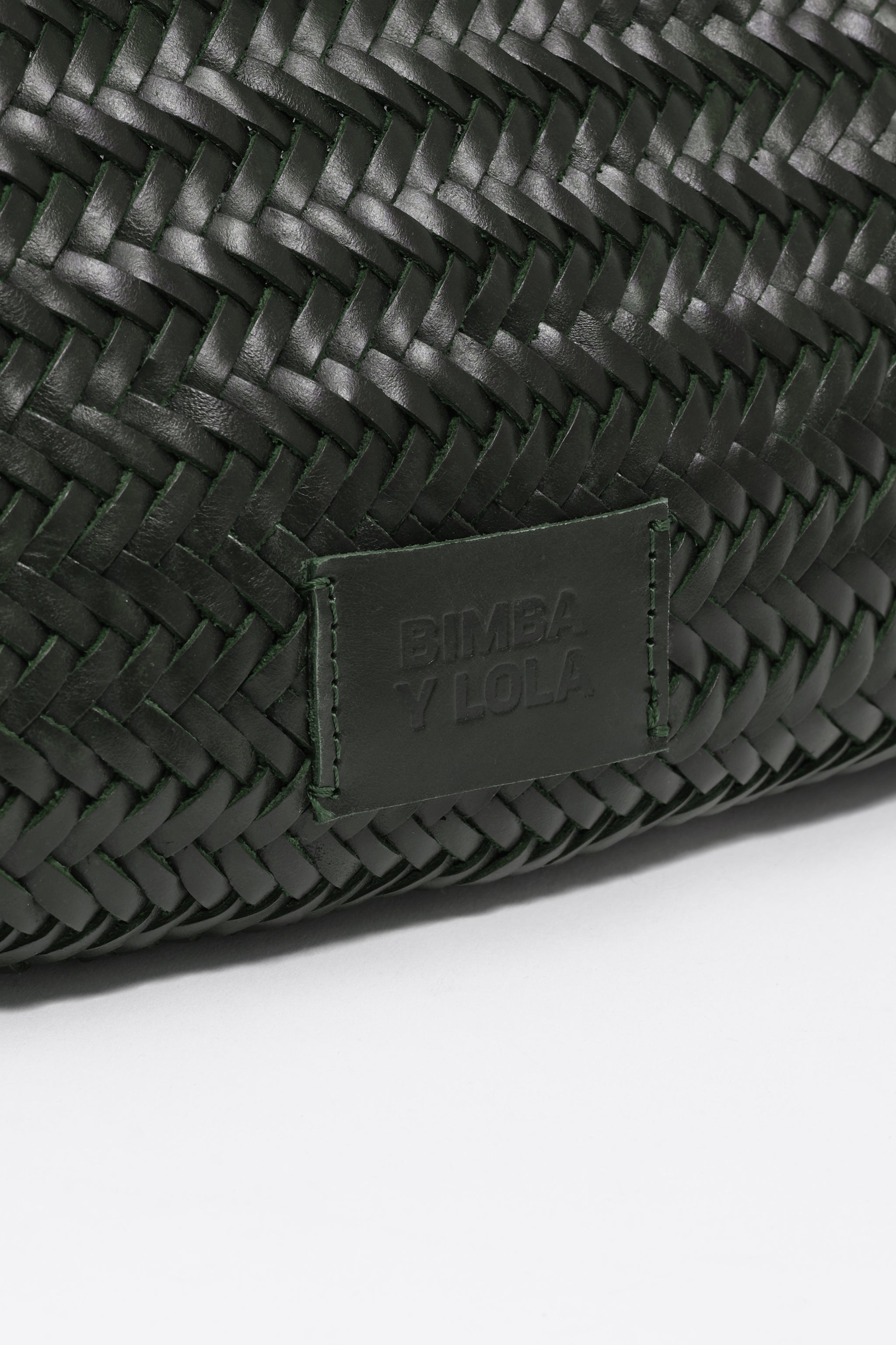 תקריב של תיק עור קלוע יוקרתי בצבע ירוק כהה עם תגית BIMBA Y LOLA, מותגים ב-CHOZEN