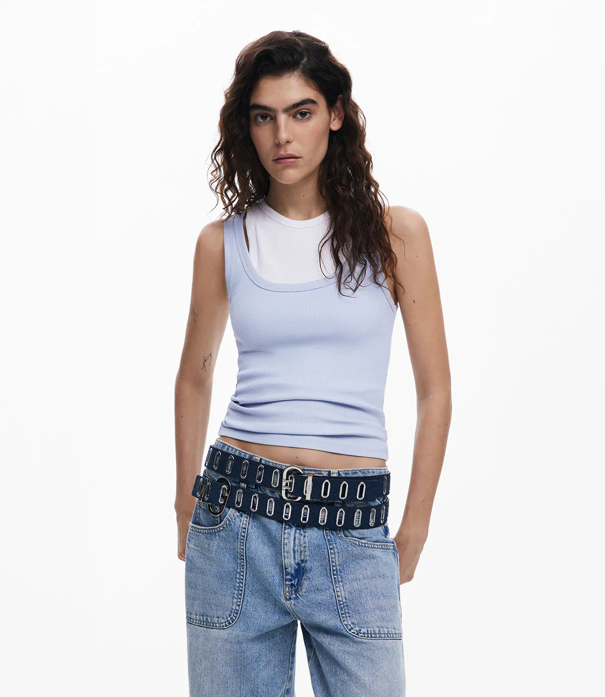 אישה עם גופיה סגולה, חגורת ג'ינס כפולה ומכנסי ג'ינס רחבים, אופנת נשים מודרנית