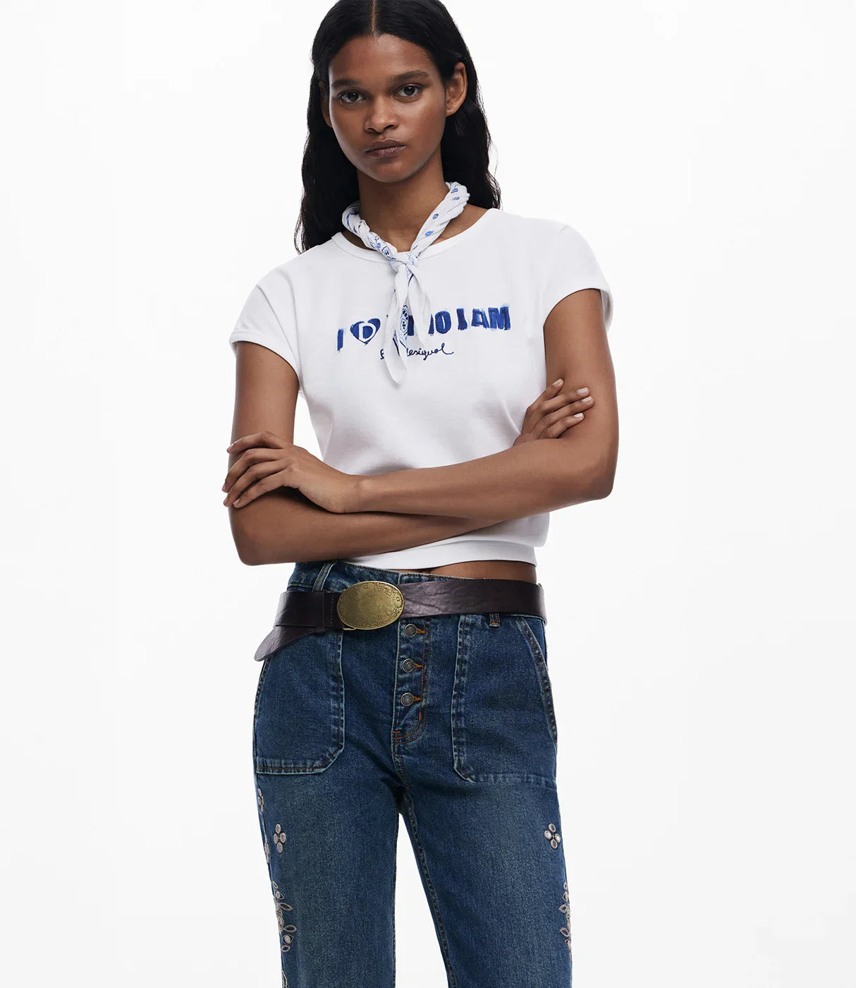 אישה עם חולצת טי לבנה עם הדפס טקסט, בנדנה לבנה צעירה בצוואר, ג'ינס כחול עם חגורה ומפתחי תפרים, סגנון אופנתי