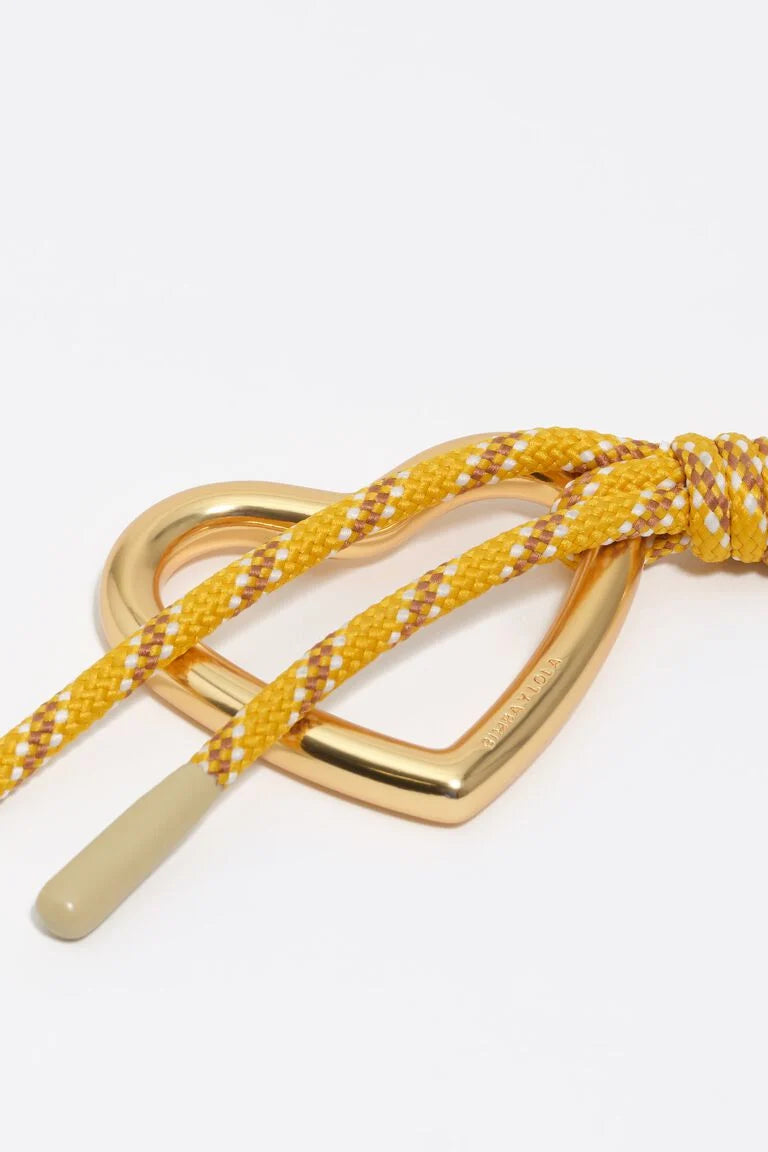 שרוך קלוע בצהוב עם קצה לבן ולולאת מתכת בצורת לב על רקע לבן