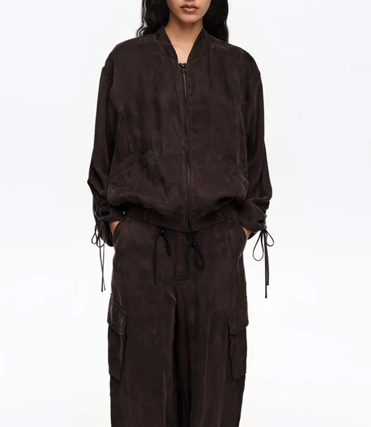 אישה לובשת מעיל בומבר כהה ומכנסי קארגו תואמים, אופנת נשים אלגנטית