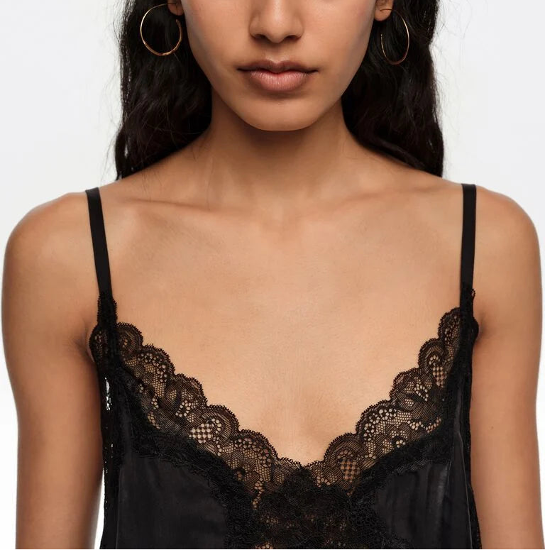 אישה לובשת גופיית סאטן שחורה עם תחרה דקה, כתפיות דקות, מראה אופנתי ועדין