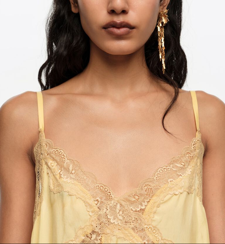 אישה לובשת שמלת כתפיות צהובה עם תחרה, עגילי זהב תלויים, אופנה אלגנטית