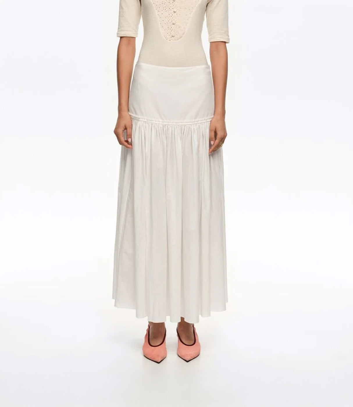 חצאית מקסי לבנה נשית בגזרה מתרחבת, נלבשת עם חולצה בז׳ ועקבים ורודים לאופנה אלגנטית