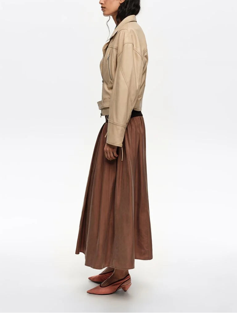 אישה עם ג'קט בז', חצאית בגוון נחושת ונעליים שטוחות, רקע לבן, אופנה נשית חורף