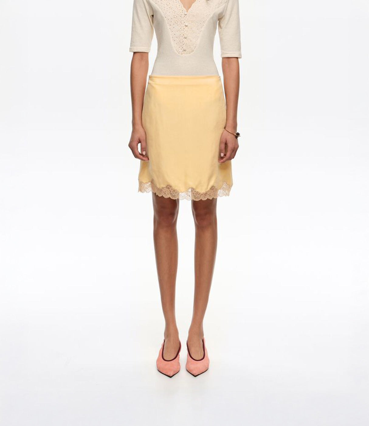 חצאית קצרה בצבע צהוב בהיר עם סיומת תחרה, חולצת חצי שרוול ונעליים ורודות