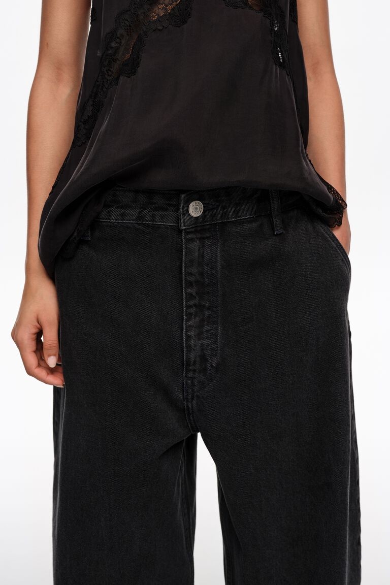 מכנסי ג'ינס רחבים בצבע שחור עם כפתור, חולצה שחורה עם תחרה לאישה