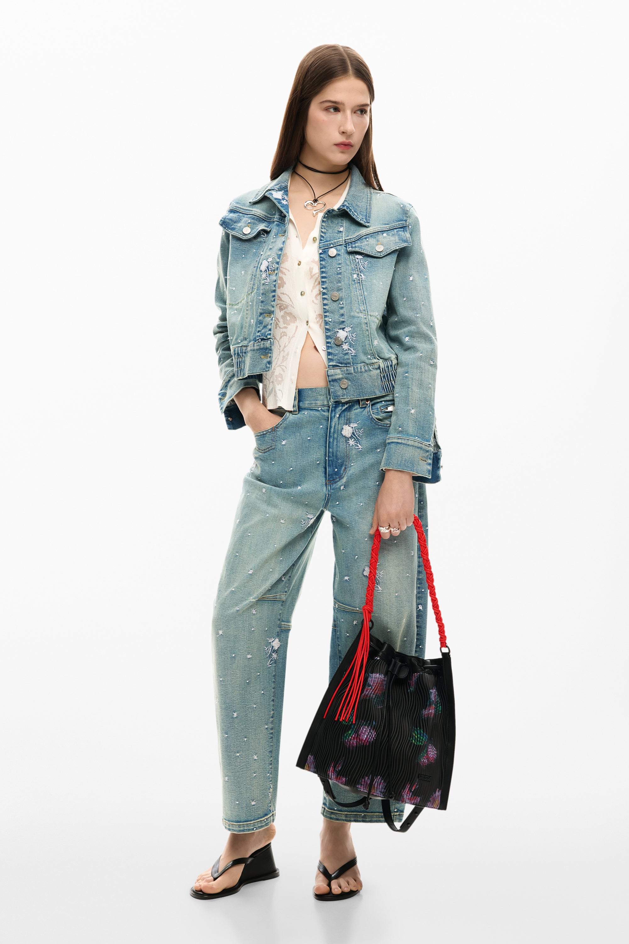 אישה לובשת ג'קט ג'ינס ומכנסי ג'ינס תואמים עם תיק יד שחור מעוצב, לוק אופנתי קז'ואל