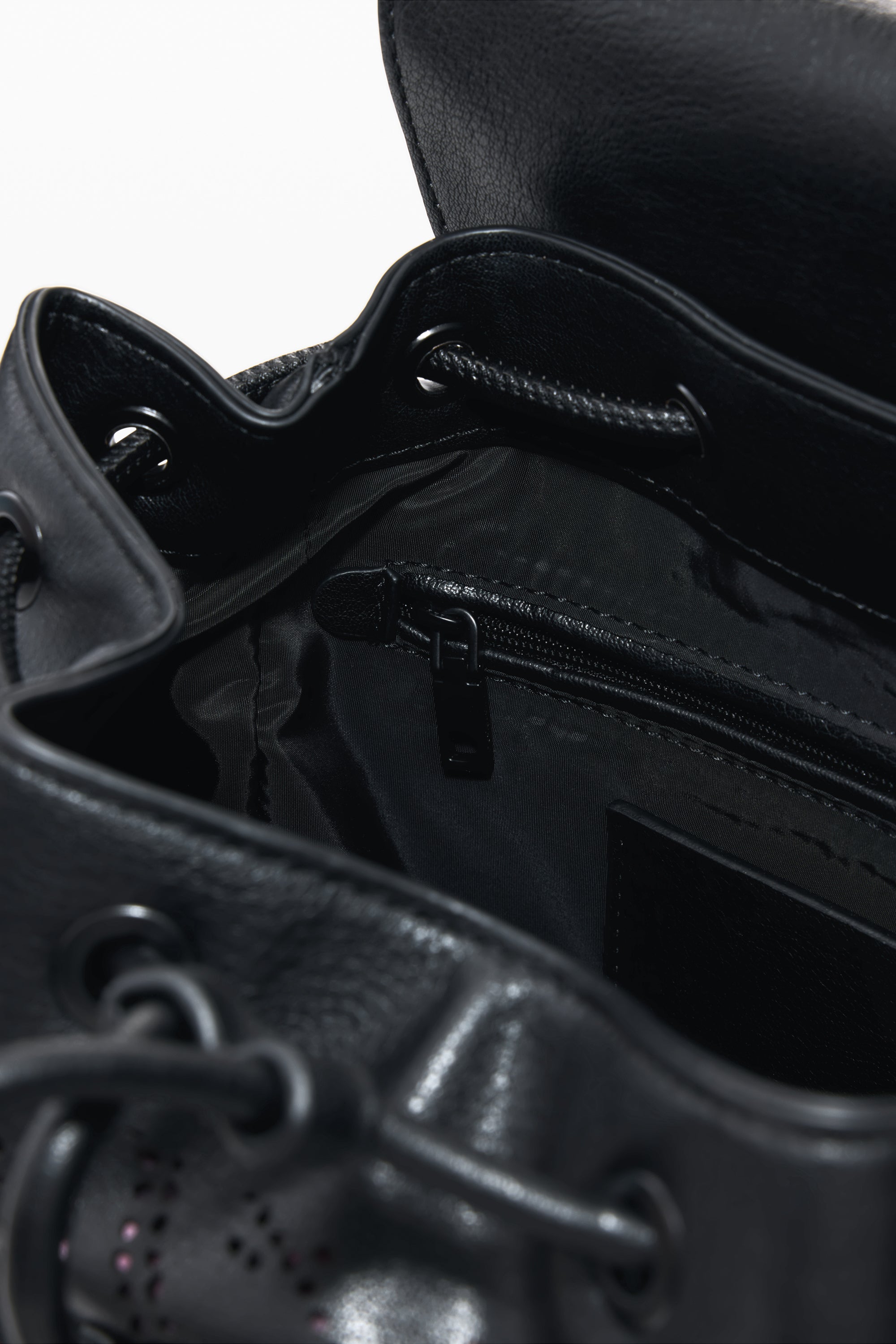 תקריב פנימי של תיק עור שחור עם כיס רוכסן ותפרים, עיצוב מודרני לאביזרי אופנה