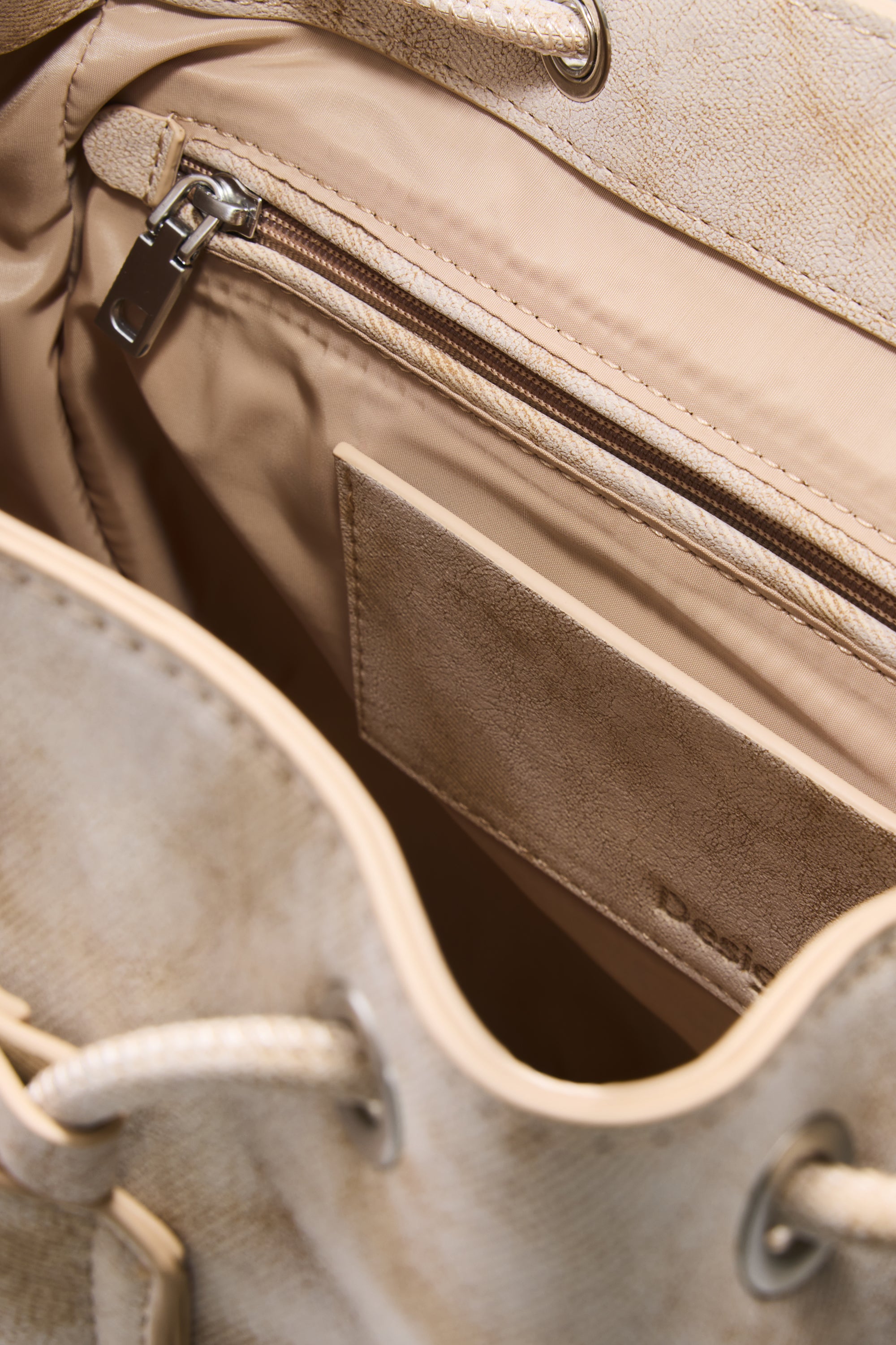 פנים תיק בד בצבע בז', תא פנימי עם רוכסן וכיס פתוח, דגש על מרקם הבד והגימור