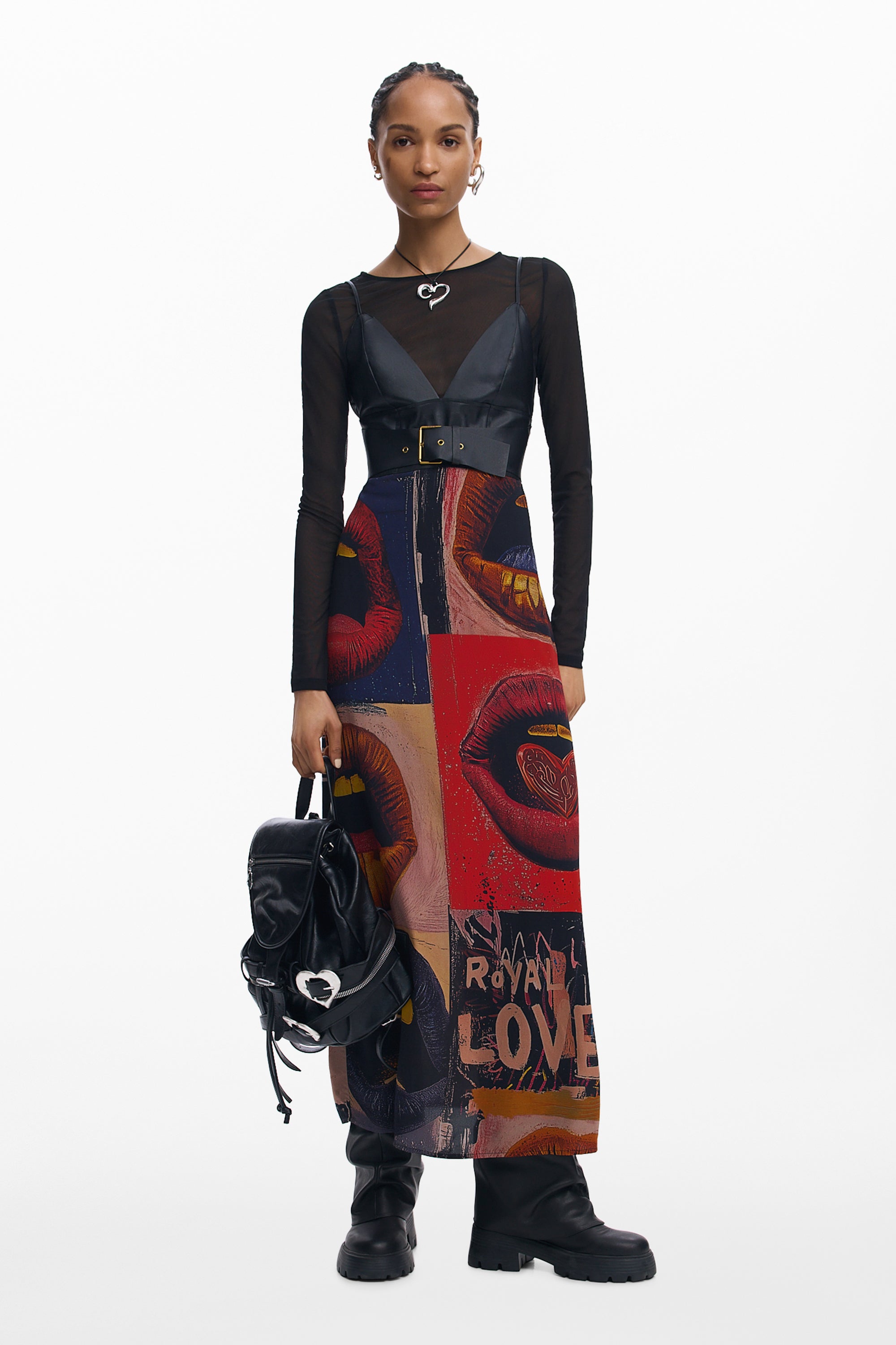 דוגמנית לובשת שמלה צבעונית עם הדפס שפתיים, עליונית שחורה, מגפיים ותיק גב שחור אופנתי