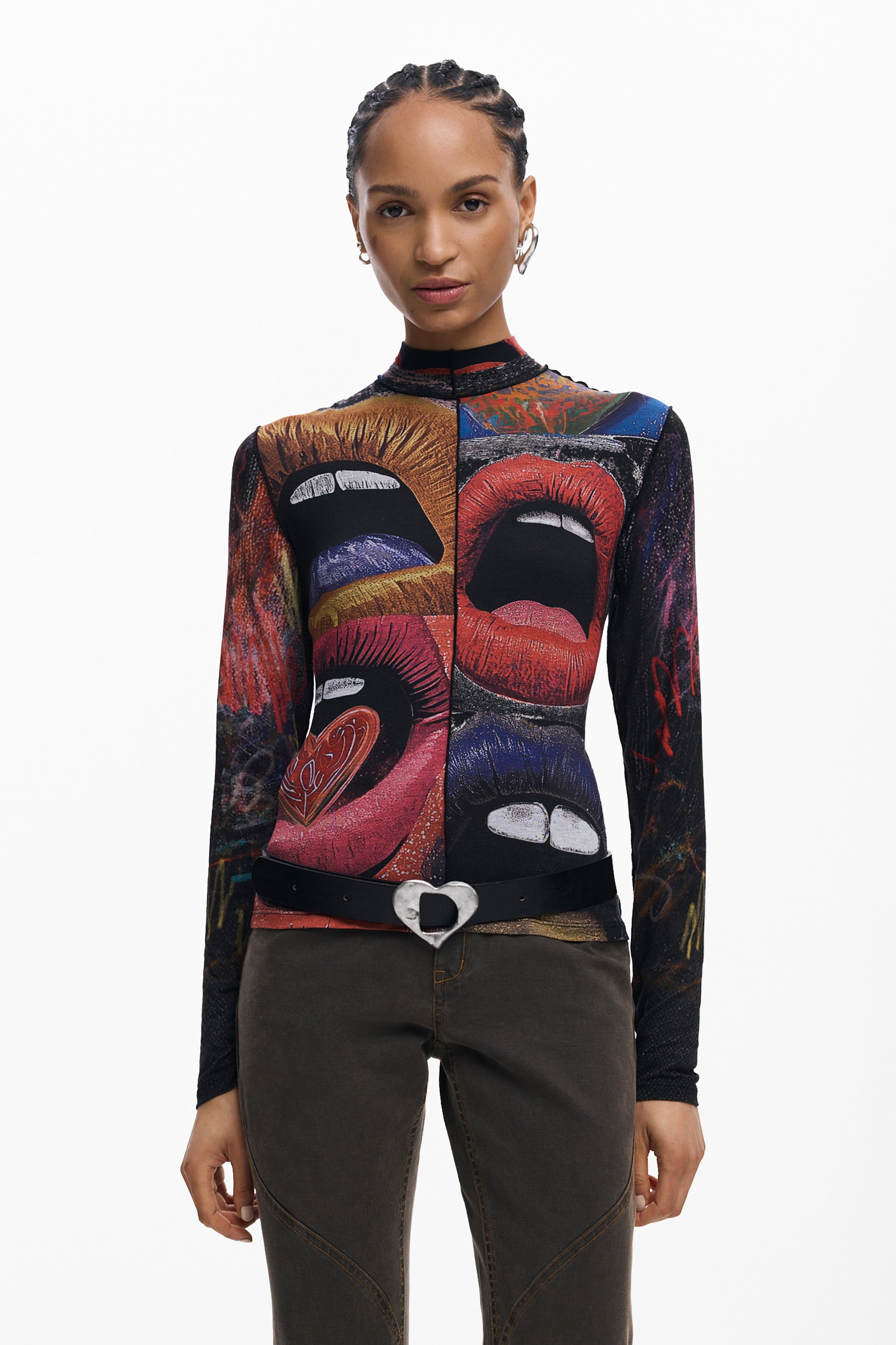 אישה לובשת חולצת טי שחורה עם הדפס אומנותי צבעוני של שפתיים, מכנסיים כהים וחגורה עם אבזם לב.